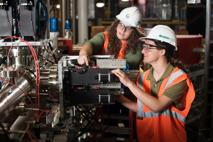 Graduate Assistant Christopher Richard (right) and Diagnostic Research Scientist Rebecca Shane inspect the controls for a system used to select ion-beam charge states.