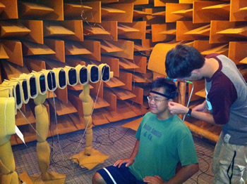 Tom is inserting tiny probe microphones into Cho's ear canals. Later, Cho will localize sounds from the 13 loudspeakers in the anechoic room, and his responses will be compared with recordings from the microphones photo