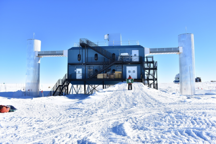 Rysewyk flying the Spartan flag in front of the IceCube laboratory at the Amundsen-Scott South Pole Station. The IceCube laboratory is the largest neutrino observatory in the world and hosts neutrino researchers from institutions around the globe.