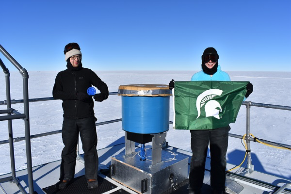 Devyn Rysewyk (R) stands next to Martin Rongen, of RWTH Aachen University in Germany and Rysewyk's teammate, and the finished particle detector prototype atop the IceCube Laboratory located at the Amundsen-Scott South Pole Station.